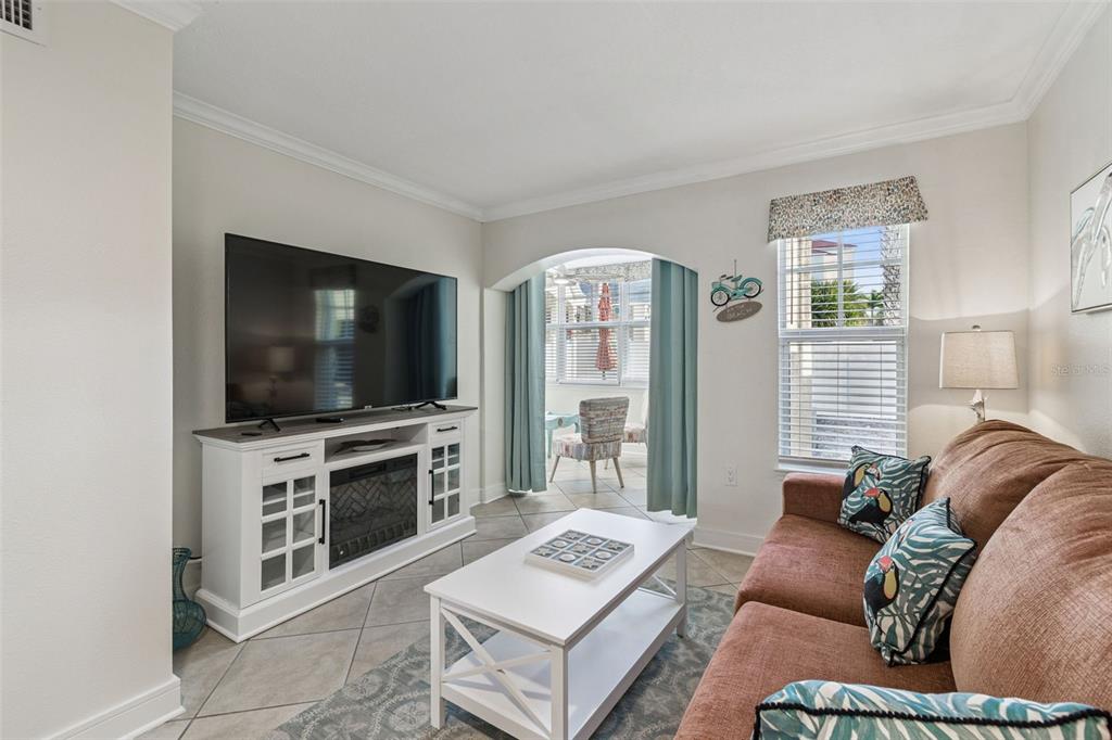 A living room features a white media console, a coffee table, and a brown sofa — 19417 GULF BOULEVARD UNIT F107, INDIAN ROCKS BEACH, FL