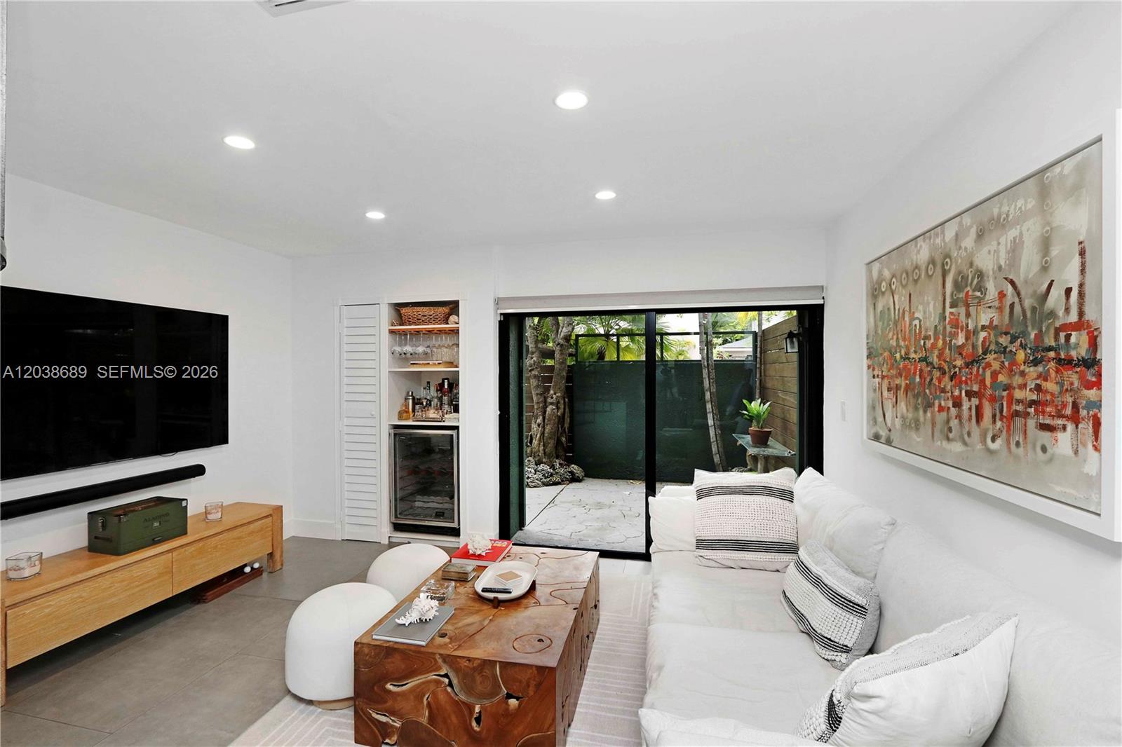 A living room features a white sofa, wooden coffee table, television, and sliding glass doors — 3138 Mary St # 3138, Miami FL 33133, MIAMI, FL