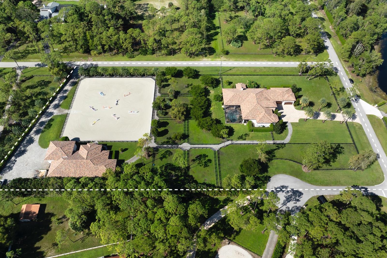 An aerial view shows a house, a horse riding arena, and fenced pastures on land — 11780 Otter Run, Lake Worth FL 33449, LAKE WORTH, FL
