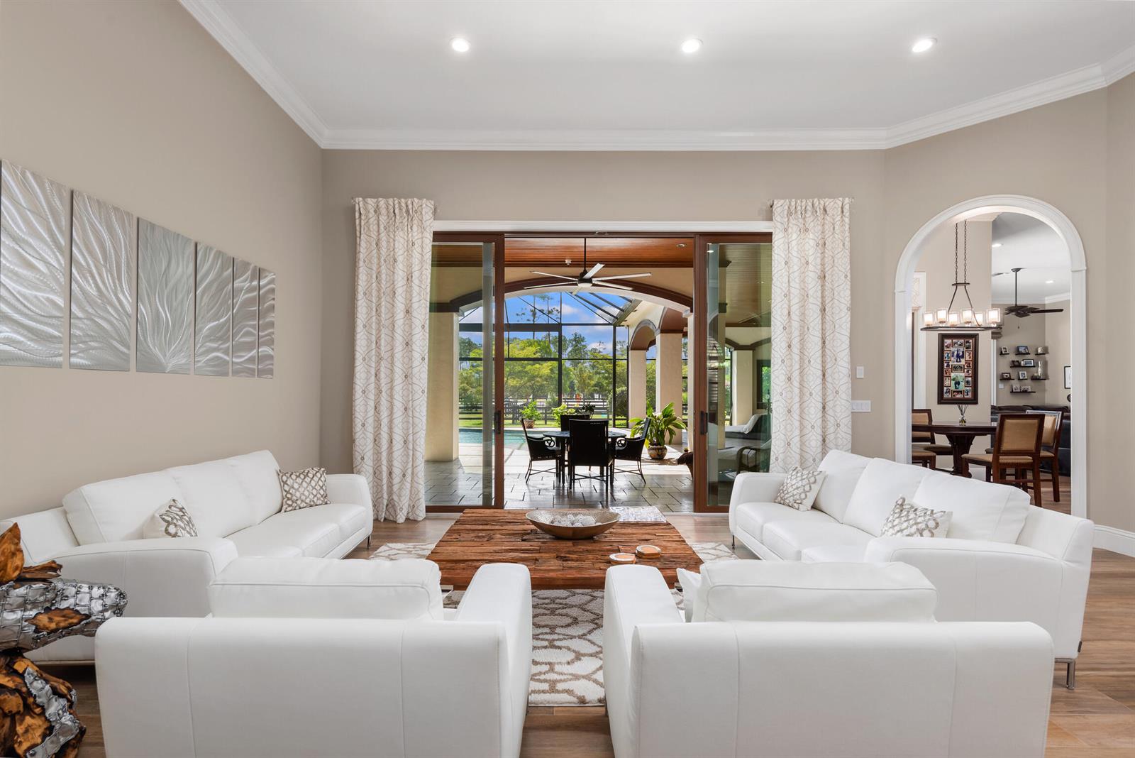 A living room with white sofas, a wooden coffee table, and sliding doors to a patio — 11780 Otter Run, Lake Worth FL 33449, LAKE WORTH, FL