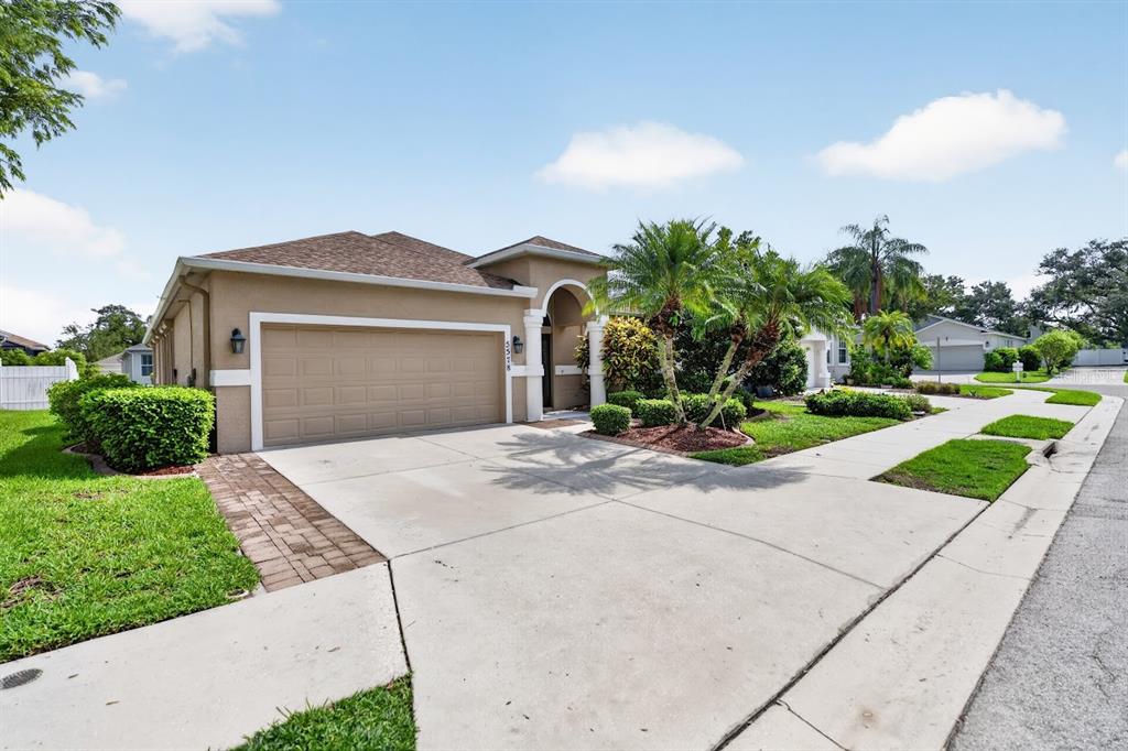 A single-story house with a tan stucco exterior, a two-car garage, and a concrete driveway — 5578 BURNT BRANCH CIRCLE, SARASOTA, FL