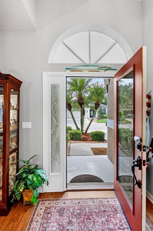 An open front door reveals a view of palm trees and a residential driveway — 5578 BURNT BRANCH CIRCLE, SARASOTA, FL