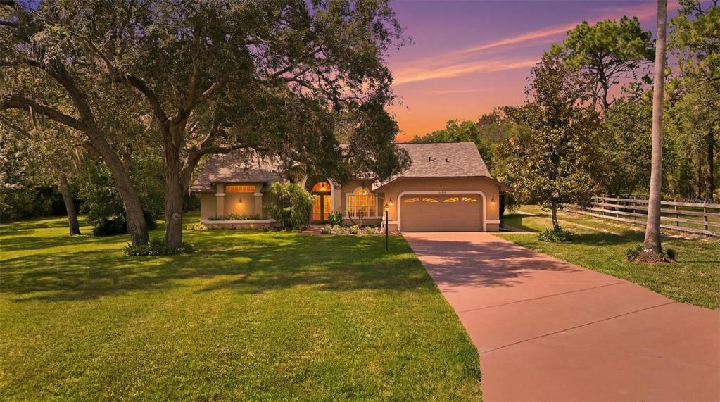 A single-story house with a two-car garage and a paved driveway sits on a lawn — 11109 GOLDEN EAGLE AVENUE, WEEKI WACHEE, FL
