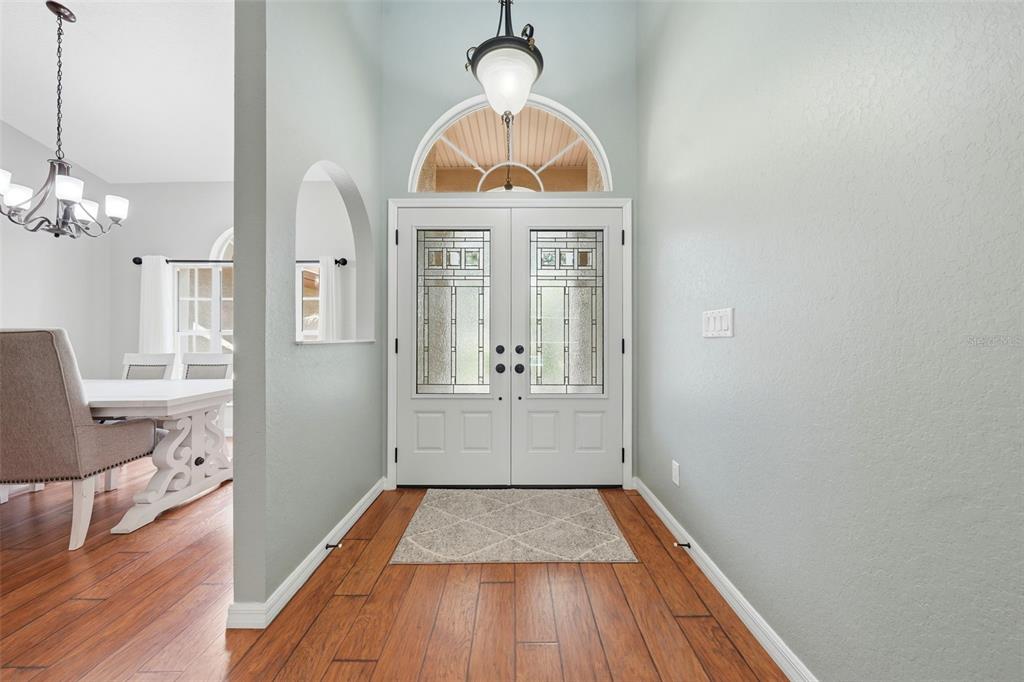 An entryway features a double front door, wood flooring, and a view into a dining room — 11109 GOLDEN EAGLE AVENUE, WEEKI WACHEE, FL