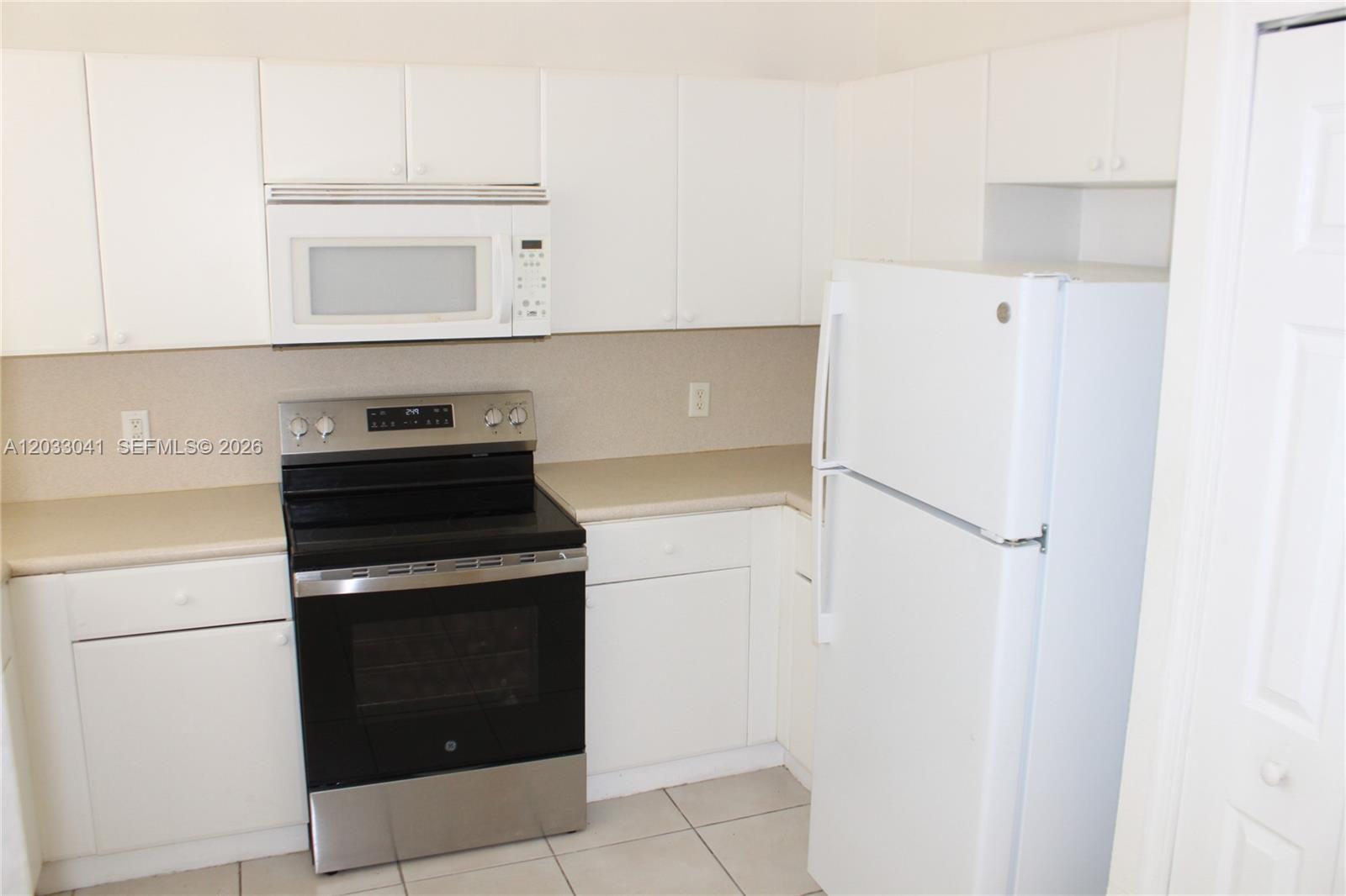 A kitchen features white cabinets, a stainless steel oven, a white microwave, and a refrigerator — 4284 SW 157th Ave # 127, Miramar FL 33027, MIRAMAR, FL