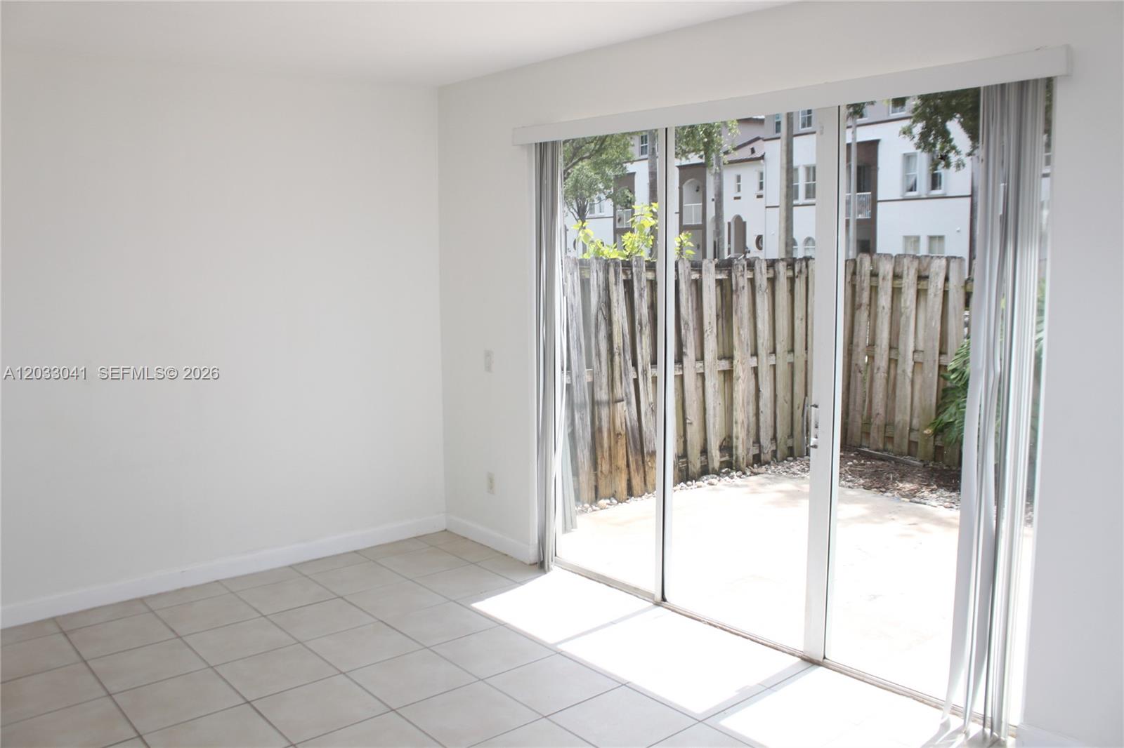A room with white walls, tiled floors, and sliding glass doors opening to a patio — 4284 SW 157th Ave # 127, Miramar FL 33027, MIRAMAR, FL