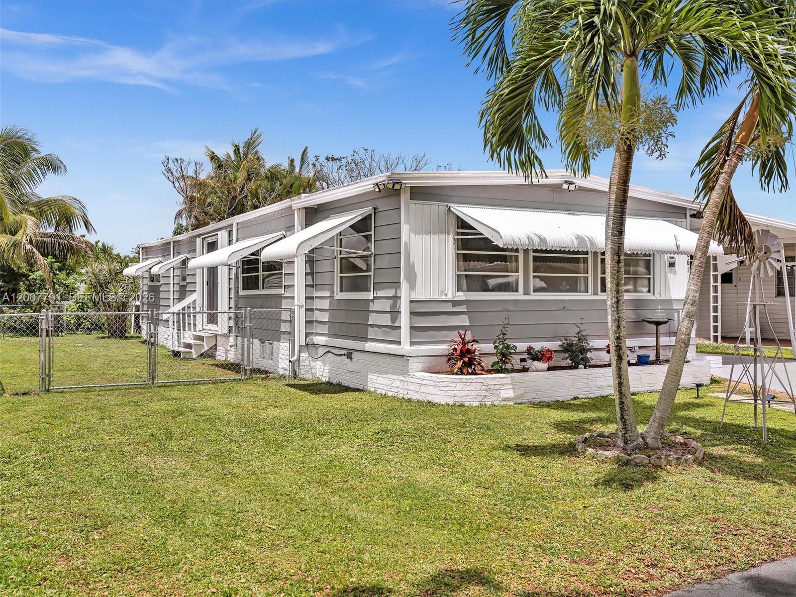 A gray mobile home with white trim and awnings sits on a grassy lawn — 2061 SW 83rd Ave, Davie FL 33324, DAVIE, FL