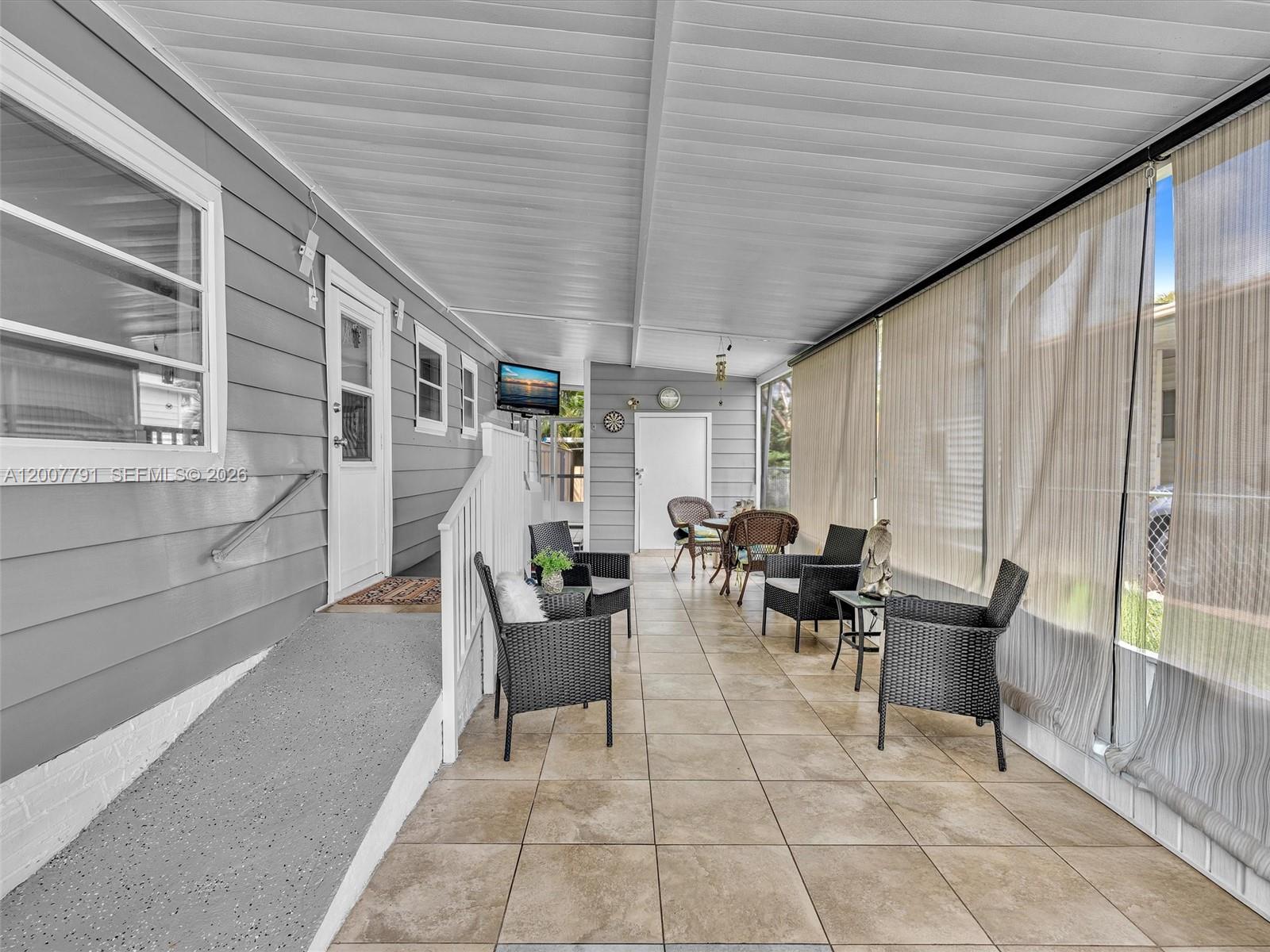 A covered outdoor patio features tiled flooring, wicker furniture, and a ramp leading to a door — 2061 SW 83rd Ave, Davie FL 33324, DAVIE, FL