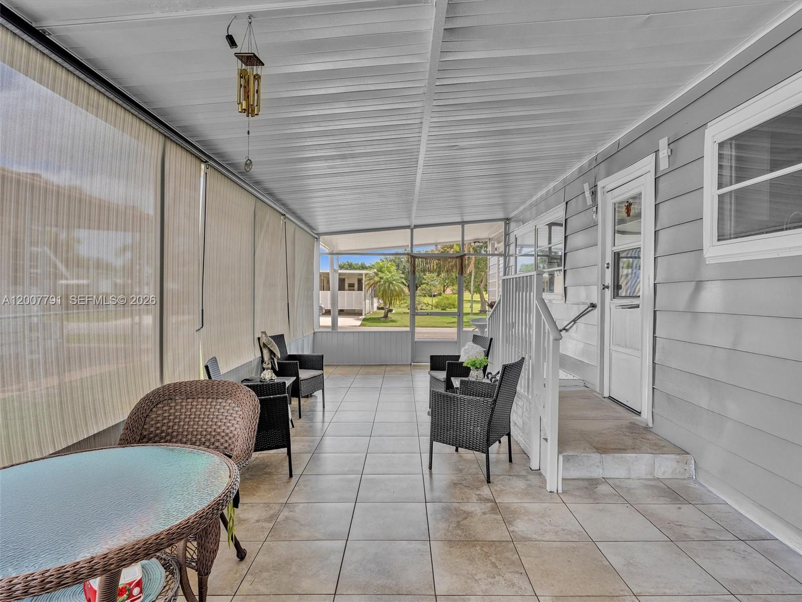 A covered patio features tiled flooring, wicker furniture, and a screened-in view of the neighborhood — 2061 SW 83rd Ave, Davie FL 33324, DAVIE, FL