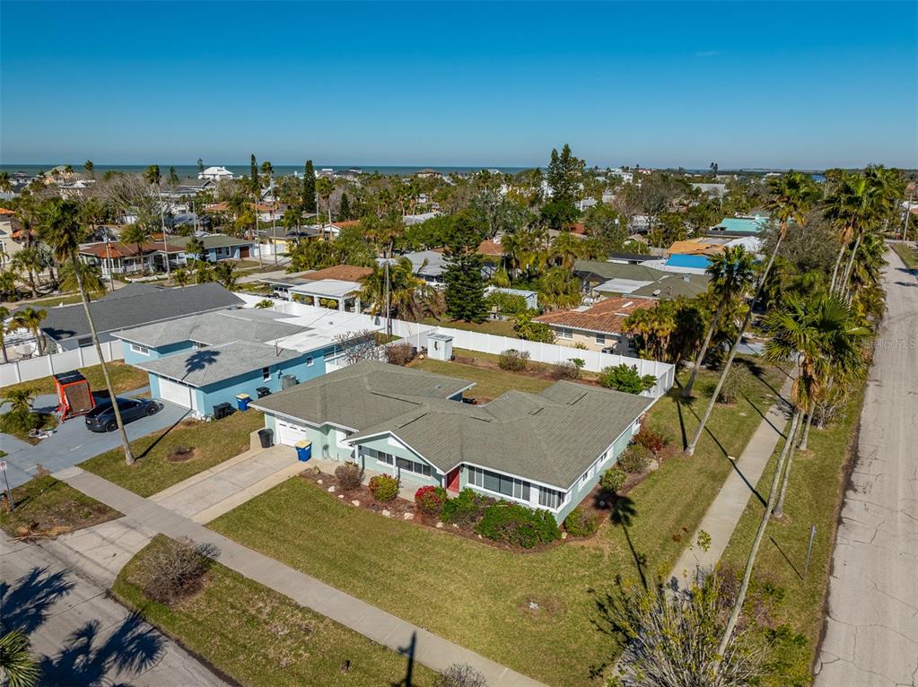 An aerial view shows a single-story house with a green roof and a large lawn — 66 KIPLING PLAZA, CLEARWATER BEACH, FL