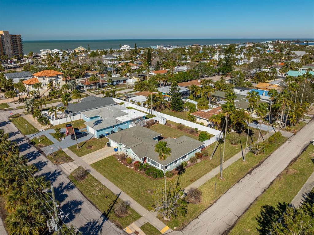 An aerial view shows a residential neighborhood with houses, palm trees, and the ocean nearby — 66 KIPLING PLAZA, CLEARWATER BEACH, FL