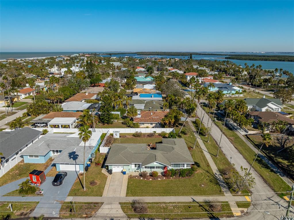 An aerial view shows a single-story house with a green roof and a paved driveway — 66 KIPLING PLAZA, CLEARWATER BEACH, FL