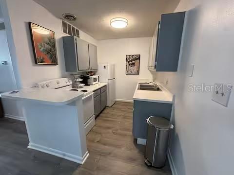 A kitchen with gray cabinets, white countertops, a stainless steel trash can, and wood-look flooring — 1700 SW 16TH COURT UNIT A5, GAINESVILLE, FL