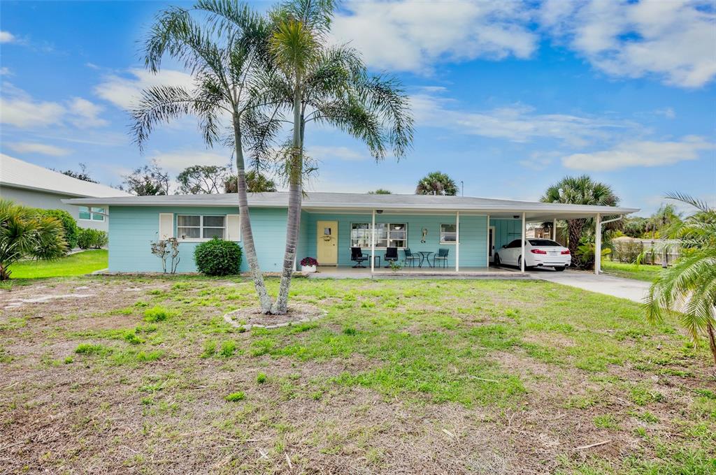 A light blue single-story house features a front porch, carport, and a palm tree — 223 ROBERTS ROAD, NOKOMIS, FL