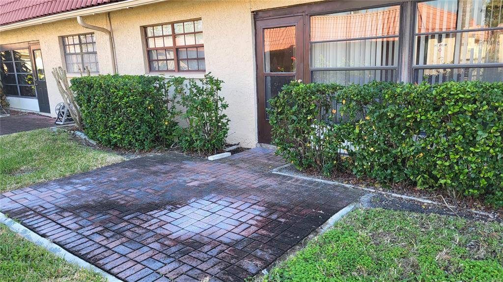 A paved patio sits in front of a building with a door and large windows — 19029 US HIGHWAY 19 N UNIT 23C, CLEARWATER, FL