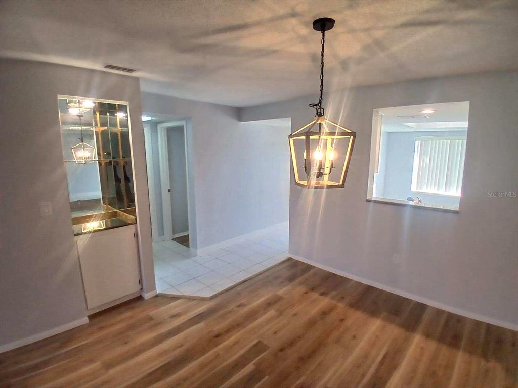 A dining area features light wood-look flooring, a geometric pendant light, and a built-in bar — 19029 US HIGHWAY 19 N UNIT 23C, CLEARWATER, FL