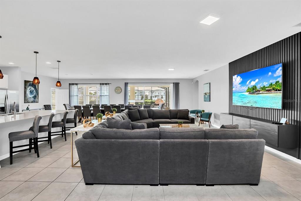 An open-concept living room features a large gray sectional sofa and a wall-mounted television — 6148 BROAD OAK DRIVE, DAVENPORT, FL