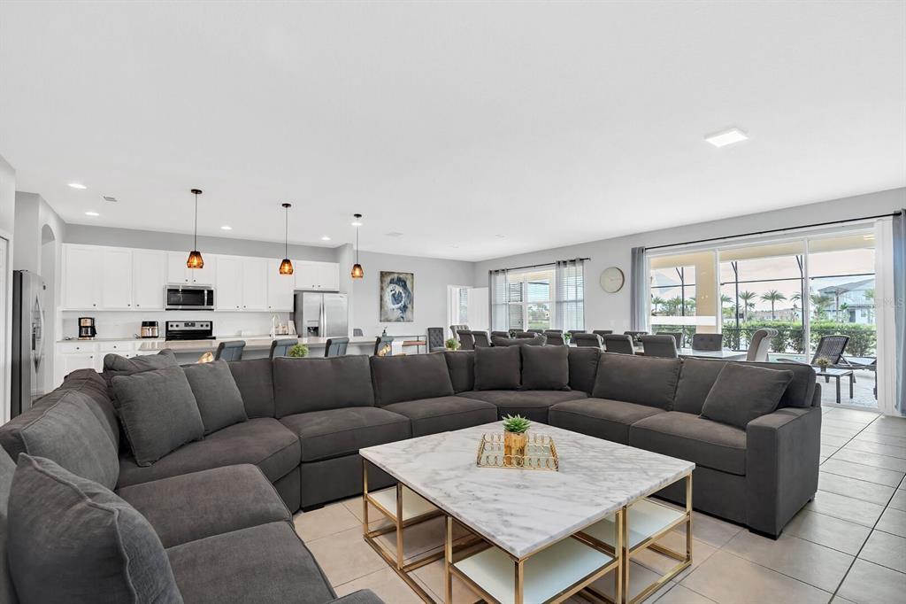 A spacious open-concept living room features a large gray sectional sofa and marble coffee table — 6148 BROAD OAK DRIVE, DAVENPORT, FL