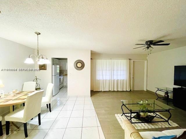 A bright, open-concept living and dining area features white tile floors and a ceiling fan — 5300 Washington St # S112, Hollywood FL 33021, HOLLYWOOD, FL