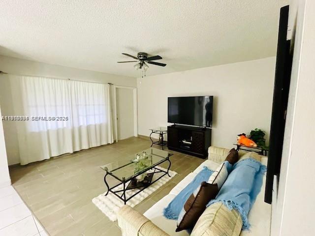 A living room features a glass coffee table, a television on a stand, and tile flooring — 5300 Washington St # S112, Hollywood FL 33021, HOLLYWOOD, FL