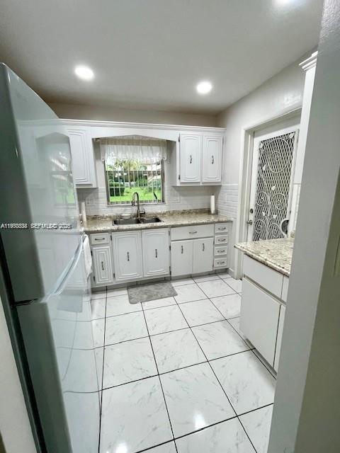 A kitchen with white cabinets, granite countertops, and white tiled flooring — 5300 Washington St # S112, Hollywood FL 33021, HOLLYWOOD, FL