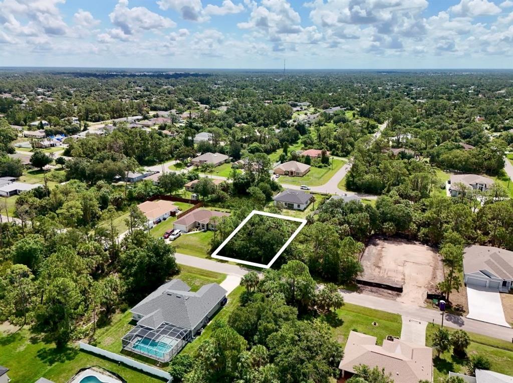 An aerial view shows a vacant, tree-covered residential lot outlined in white in a neighborhood — NANTUCKET TERRACE, NORTH PORT, FL