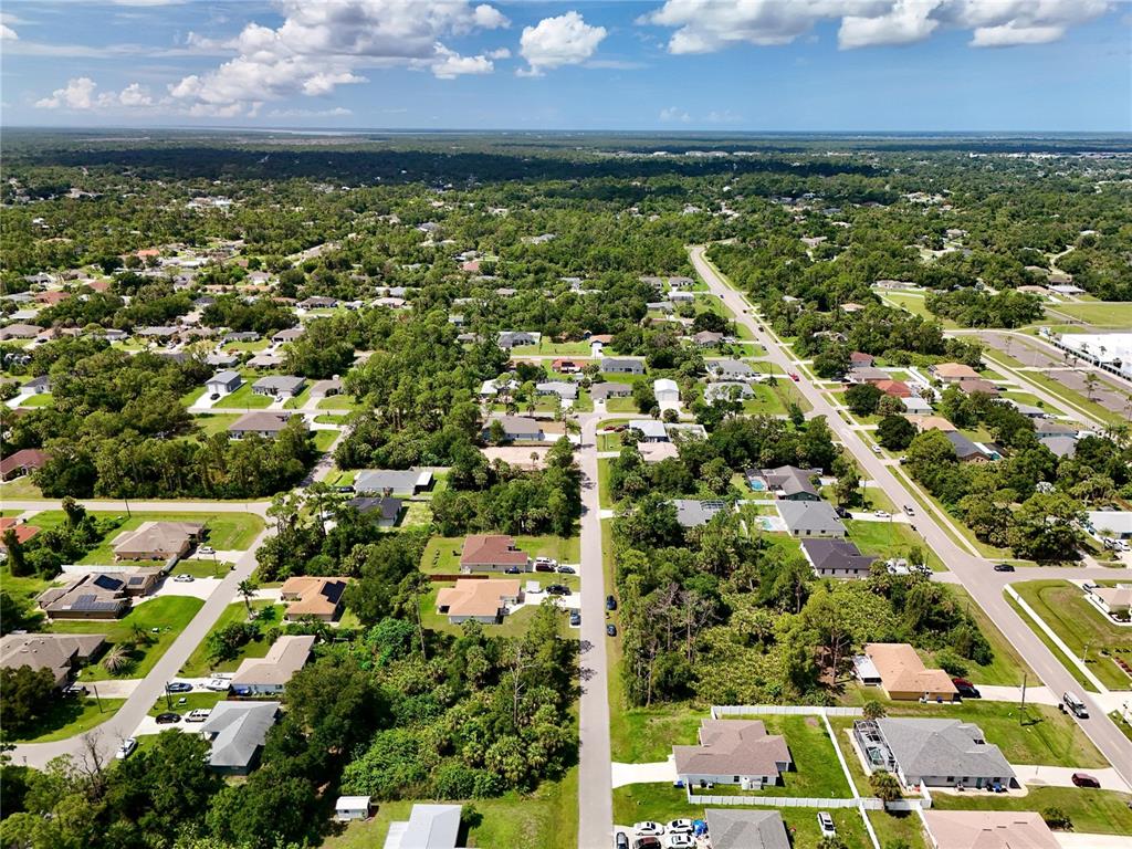An aerial view shows a suburban neighborhood with houses surrounded by dense green trees — NANTUCKET TERRACE, NORTH PORT, FL