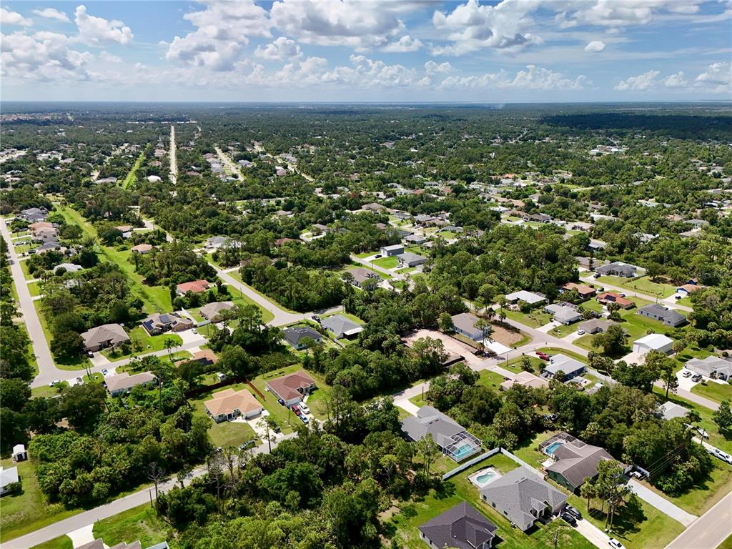 An aerial view shows a suburban neighborhood with houses, swimming pools, and dense green trees — NANTUCKET TERRACE, NORTH PORT, FL