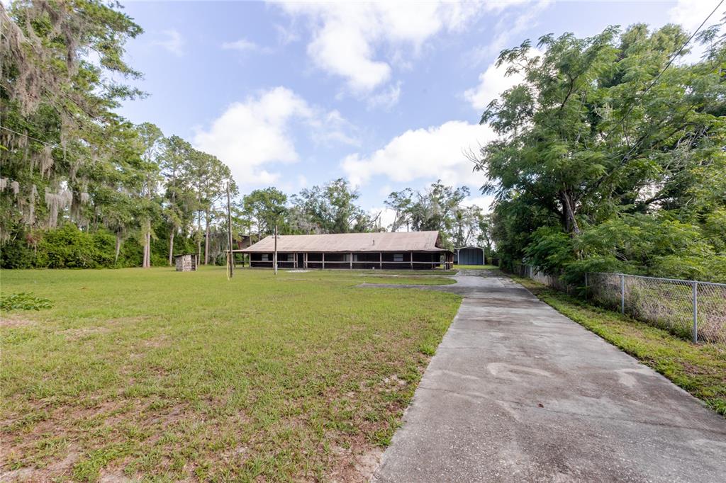 A long, single-story house with a covered porch sits on a large, grassy lot — 13203 BLISSFIELD, ODESSA, FL