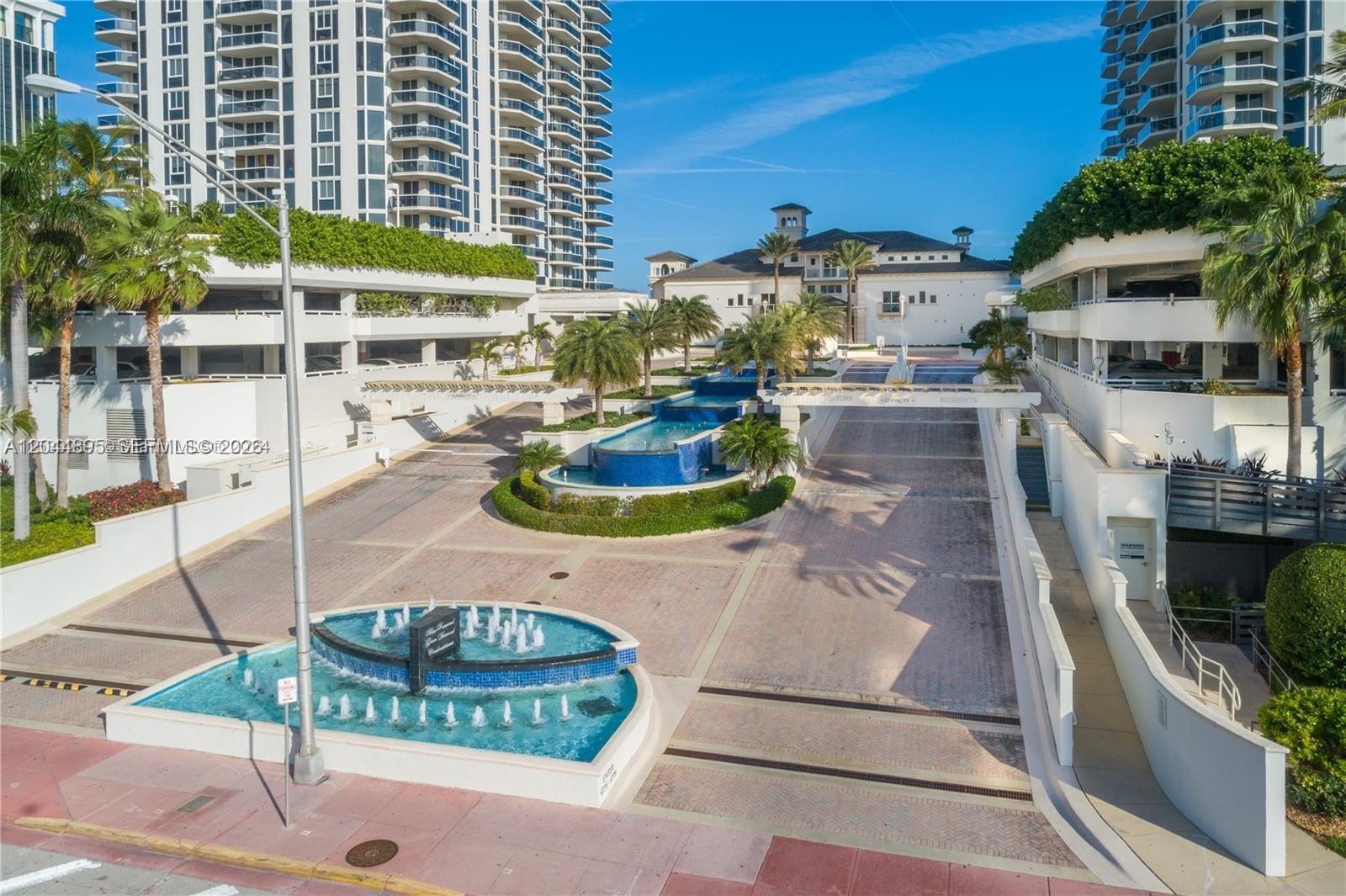 An aerial view of a paved driveway entrance featuring tiered fountains and palm trees — 4779 Collins Ave # 3102, Miami Beach FL 33140, MIAMI BEACH, FL