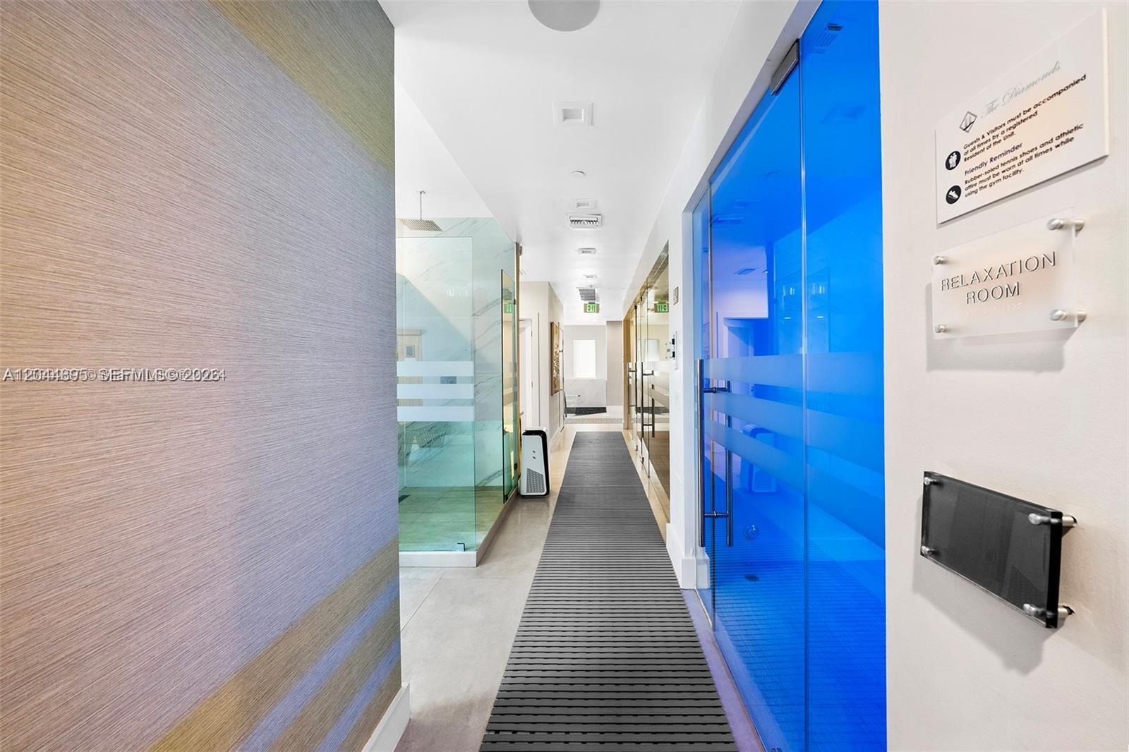 A hallway features a blue glass door, a glass-enclosed shower, and a gray floor mat — 4779 Collins Ave # 3102, Miami Beach FL 33140, MIAMI BEACH, FL