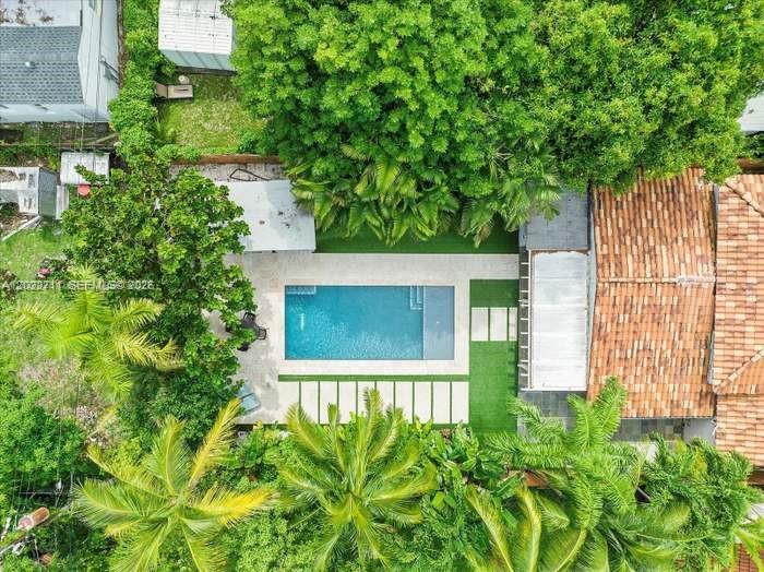 An aerial view shows a rectangular swimming pool surrounded by a patio and lush trees — 443 NE 71st St, Miami FL 33138, MIAMI, FL