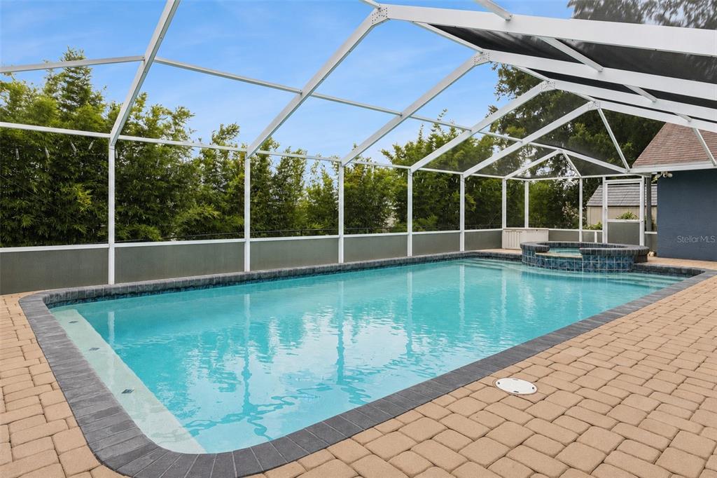 A rectangular swimming pool with an attached spa is enclosed by a white screen cage — 2352 MILES COURT, LAKELAND, FL