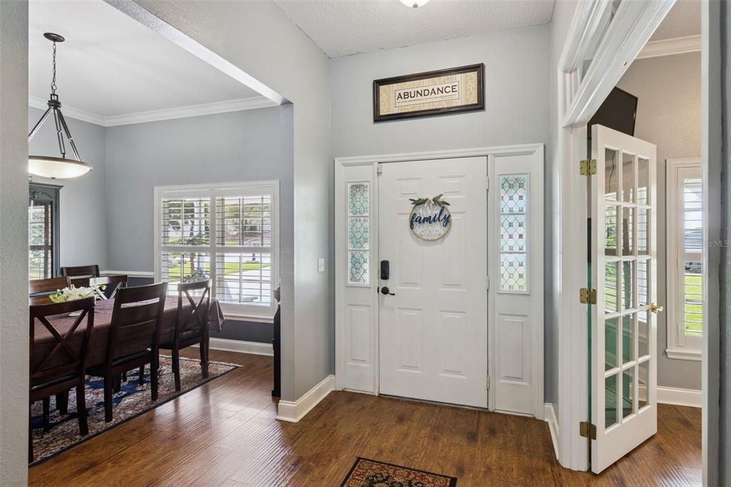 An entryway with hardwood floors, a white front door, and an adjacent dining room — 2352 MILES COURT, LAKELAND, FL