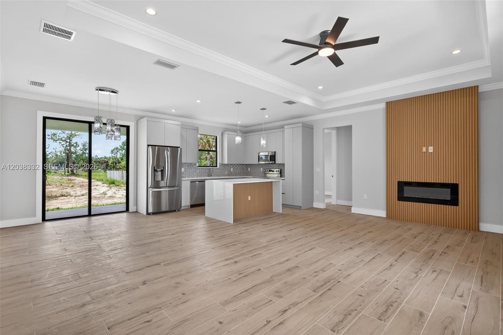 A modern open-concept kitchen and living area features light wood-look tile flooring and a fireplace — 8248 SUN N LAKE BLVD, Sebring FL 33872, SEBRING, FL