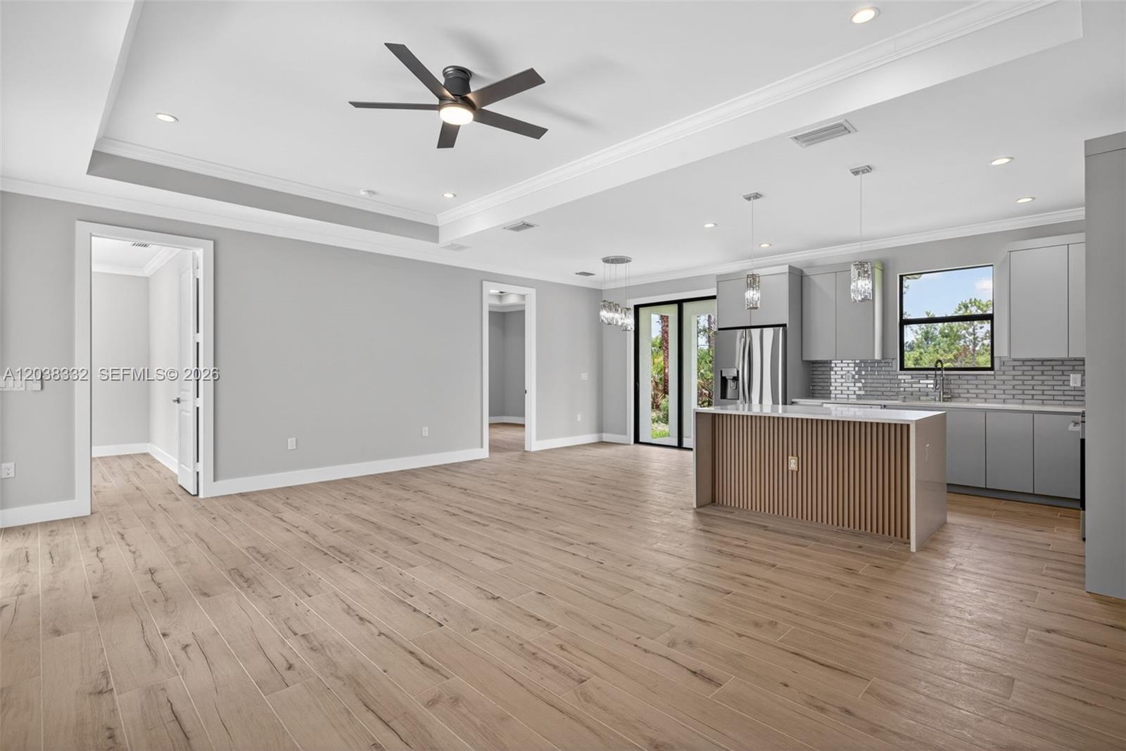 A modern open-concept kitchen and living area features light wood floors and gray cabinetry — 8248 SUN N LAKE BLVD, Sebring FL 33872, SEBRING, FL