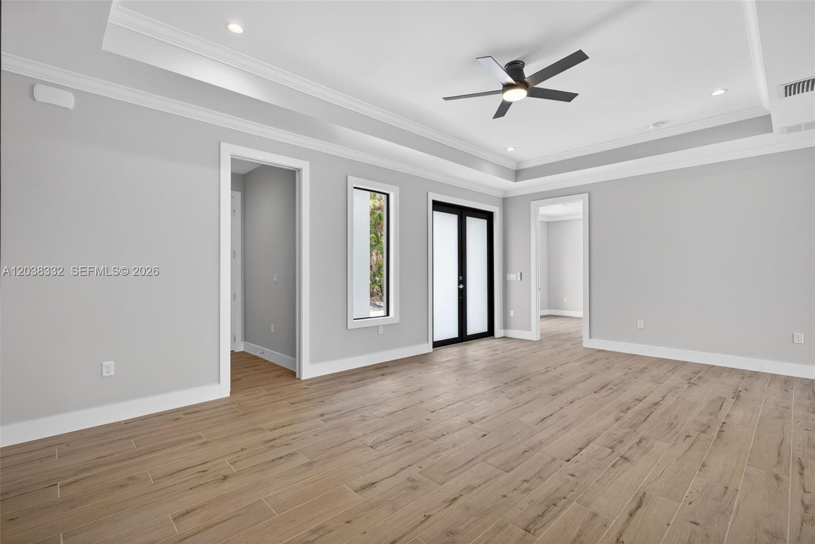 A room with light gray walls, wood-look tile flooring, a tray ceiling, and black-framed doors — 8248 SUN N LAKE BLVD, Sebring FL 33872, SEBRING, FL