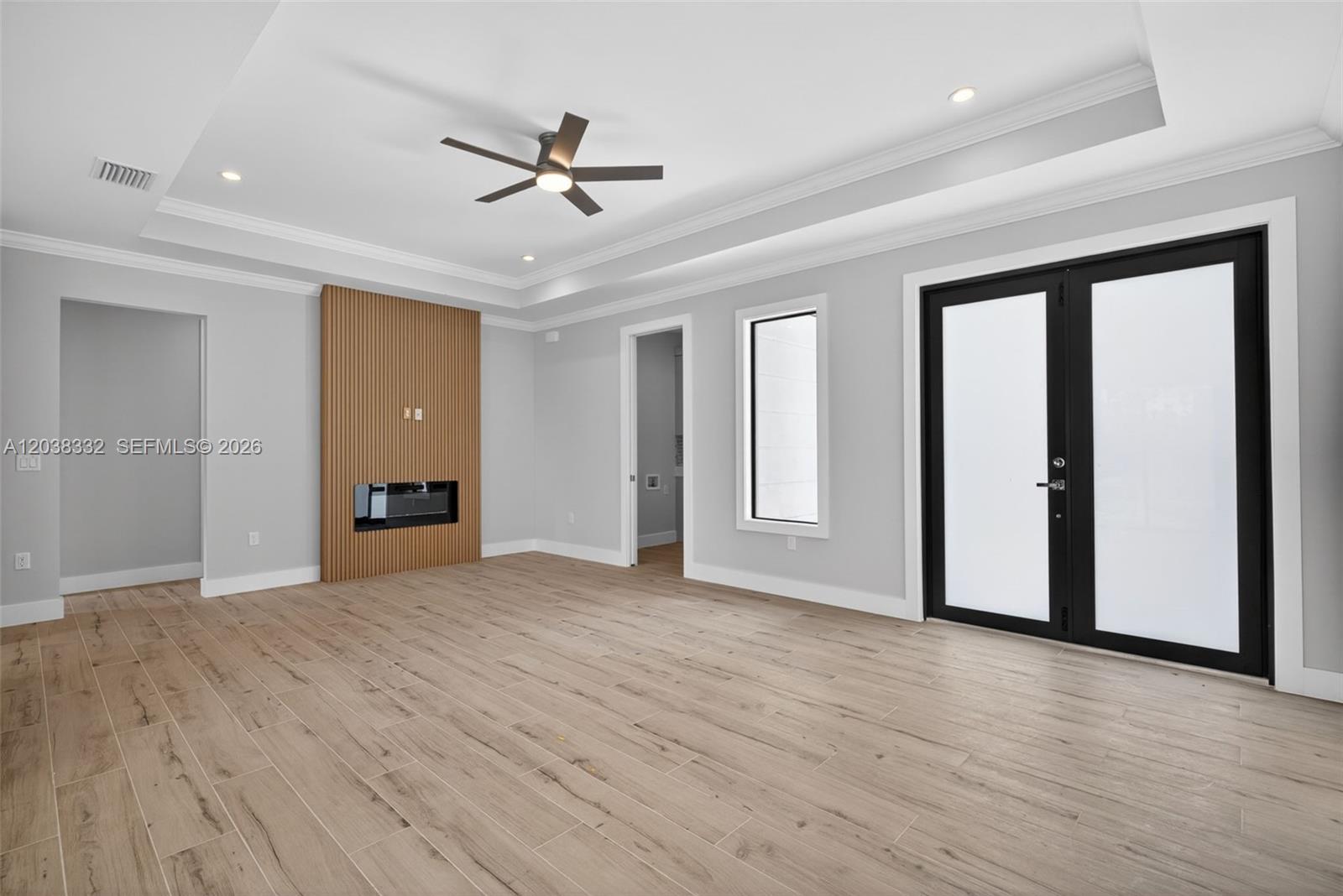 A living room features light wood-look tile flooring, a slatted wood fireplace wall, and double doors — 8248 SUN N LAKE BLVD, Sebring FL 33872, SEBRING, FL
