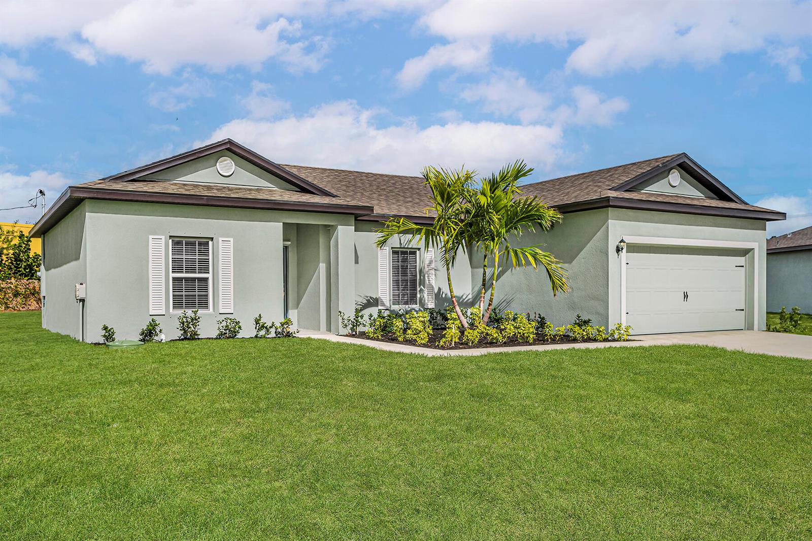 A single-story house with light green stucco, a two-car garage, and a palm tree — 7855 104th Avenue, Vero Beach FL 32967, VERO BEACH, FL