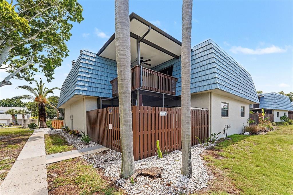 A two-story building with a blue mansard roof, a wooden balcony, and a privacy fence — 14521 CATALINA CIRCLE, SEMINOLE, FL