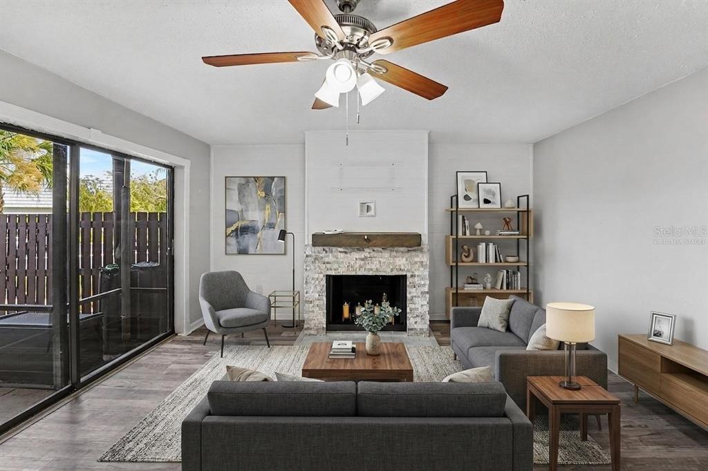 A living room features a stone fireplace, a ceiling fan, and sliding glass patio doors — 14521 CATALINA CIRCLE, SEMINOLE, FL