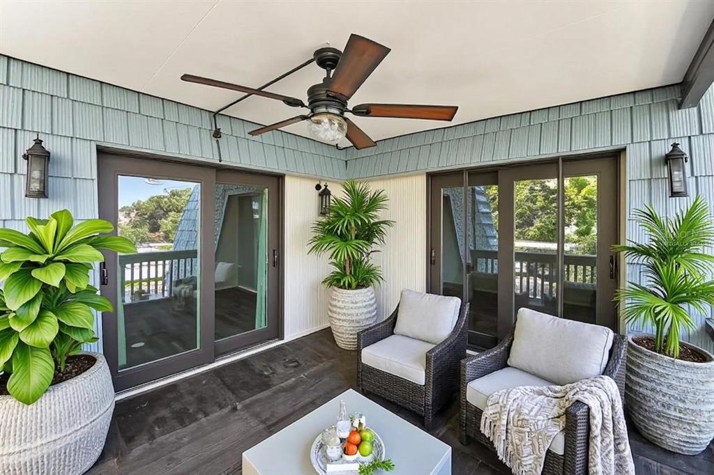 A covered balcony features dark wood flooring, two wicker chairs, potted plants, and a ceiling fan — 14521 CATALINA CIRCLE, SEMINOLE, FL
