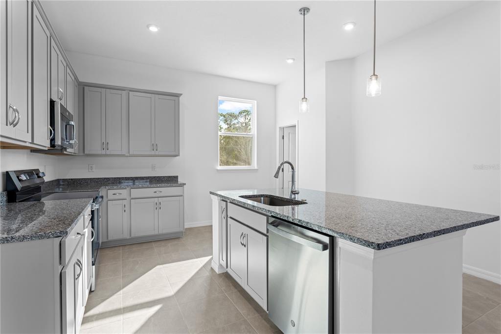 A kitchen with gray cabinets, granite countertops, a center island, and stainless steel appliances — 9614 MONTAGUE STREET, WESTCHASE, FL