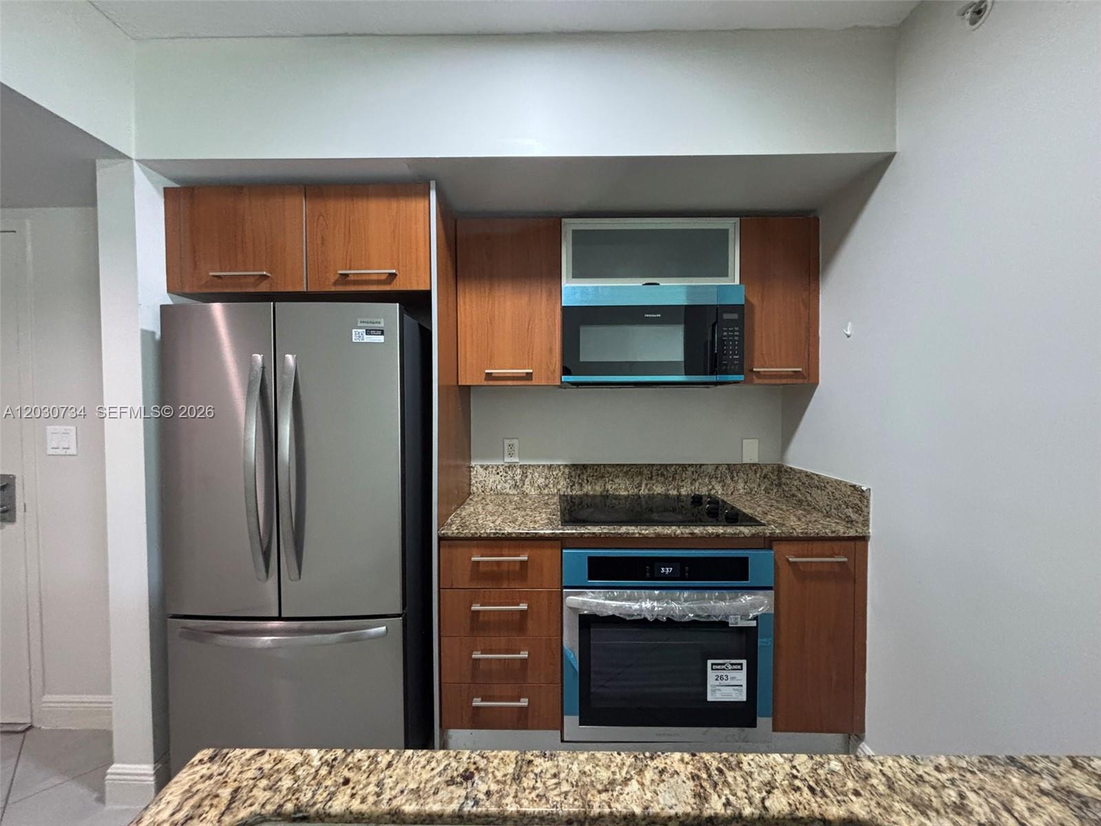 A kitchen features stainless steel appliances, wood cabinets, and granite countertops — 9055 SW 73rd Ct # 1504, Miami FL 33156, MIAMI, FL