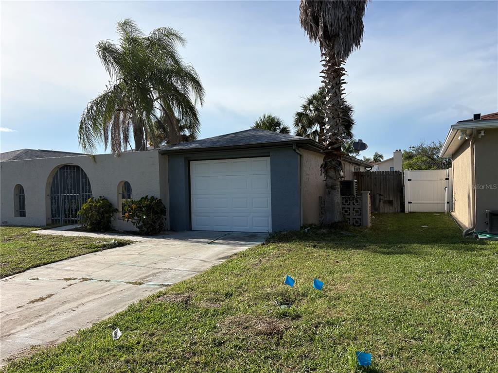 A single-story house with a white garage door, concrete driveway, and palm trees — 6301 SEABREEZE DRIVE, PORT RICHEY, FL