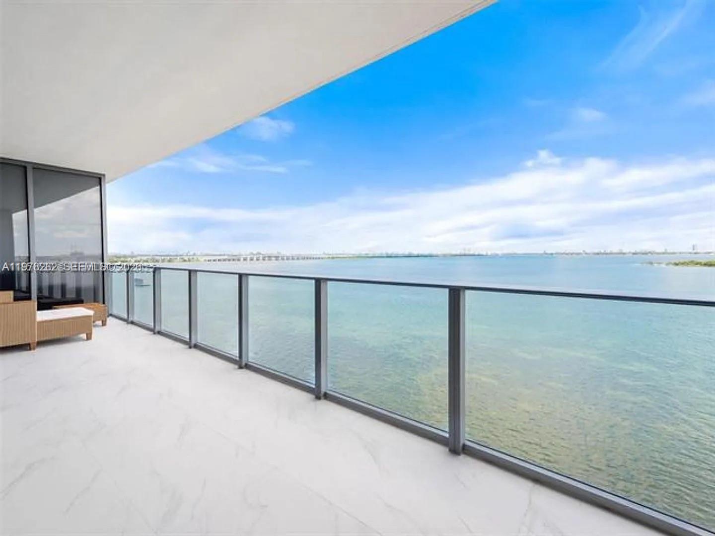 A balcony with a glass railing overlooks a large body of water under a blue sky — 700 NE 24TH ST # 606, Miami FL 33137, MIAMI, FL