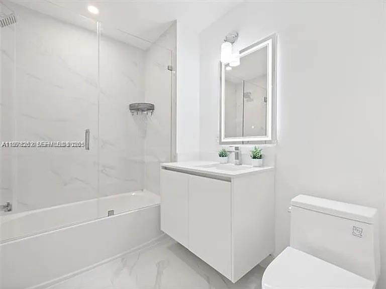 A modern bathroom features a white vanity, a glass-enclosed shower, and a toilet — 700 NE 24TH ST # 606, Miami FL 33137, MIAMI, FL