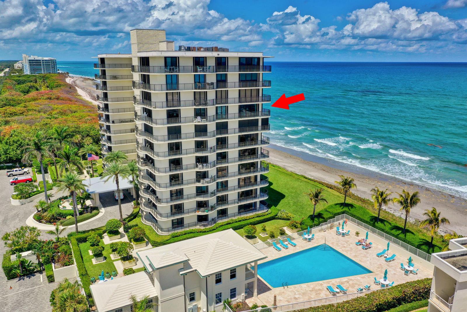 An aerial view of a beachfront condominium building with a pool and a red arrow — 400 Beach Road # 804, Tequesta FL 33469, TEQUESTA, FL