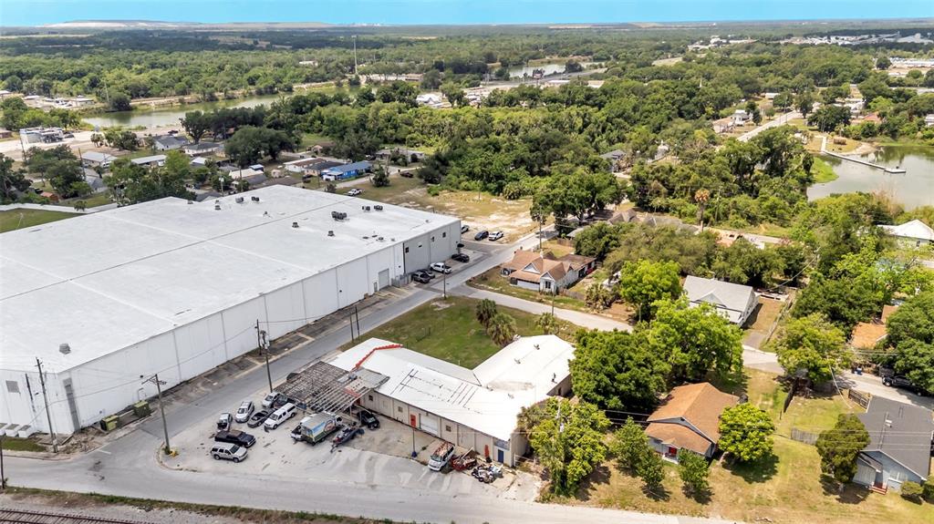An aerial view shows a large warehouse building next to smaller commercial and residential structures — 400 NW PHOSPHATE BOULEVARD, MULBERRY, FL