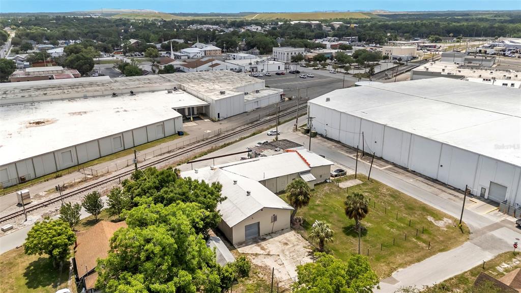 An aerial view shows a small industrial building situated between two large warehouses and railroad tracks — 400 NW PHOSPHATE BOULEVARD, MULBERRY, FL